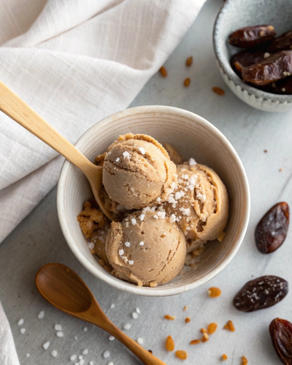 salted-miso-date-creami-featured Top-down view of Salted Miso Date Creami in a ceramic bowl with flaky sea salt and wooden spoon